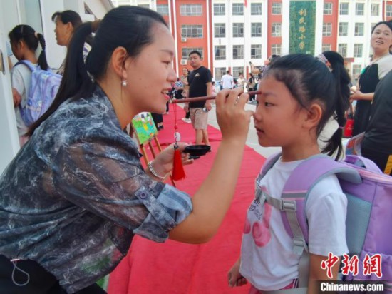 图为衡水市利民路小学，老师为学生点朱砂痣，寓意开启智慧。张松 摄